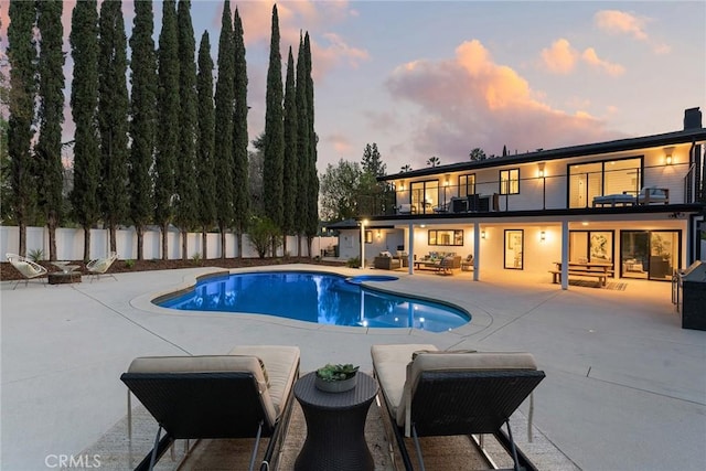 pool at dusk with a patio area, a fenced backyard, outdoor lounge area, and a fenced in pool