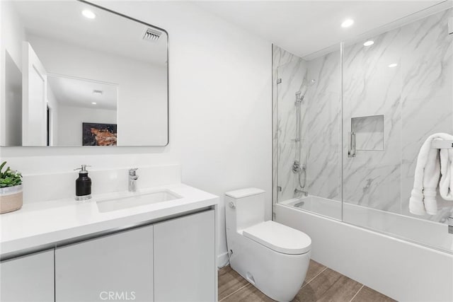 bathroom featuring recessed lighting, enclosed tub / shower combo, toilet, and wood finished floors