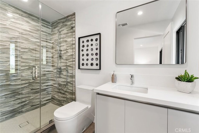 bathroom with visible vents, a shower stall, toilet, and vanity