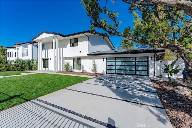 view of front of house featuring a front yard, concrete driveway, an attached garage, and stucco siding