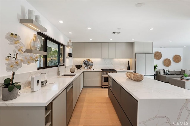 kitchen with a kitchen island, a sink, visible vents, appliances with stainless steel finishes, and modern cabinets