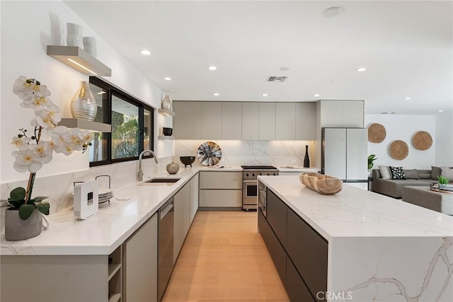 kitchen featuring appliances with stainless steel finishes, a sink, a center island, visible vents, and modern cabinets