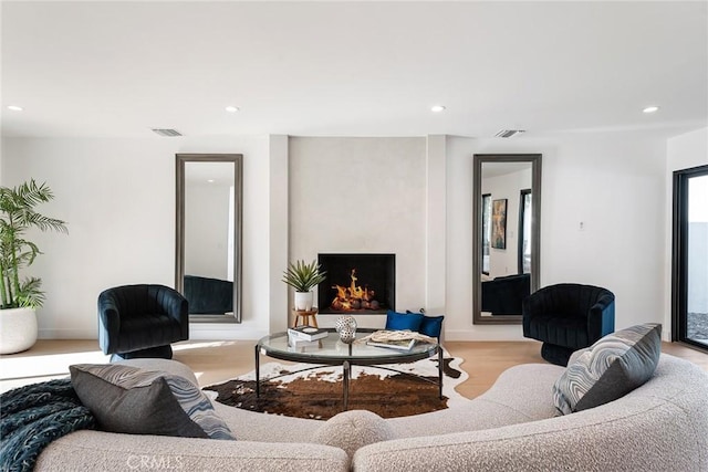 living room with a large fireplace, visible vents, and recessed lighting