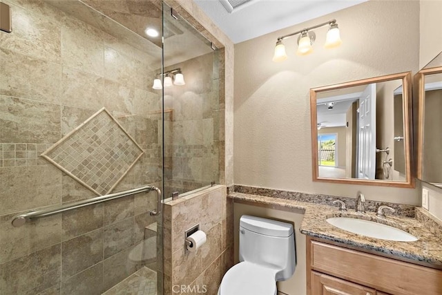 bathroom with visible vents, a textured wall, toilet, vanity, and a shower stall