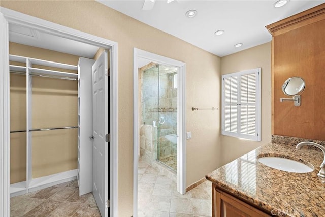 full bath featuring recessed lighting, a spacious closet, a shower stall, vanity, and baseboards