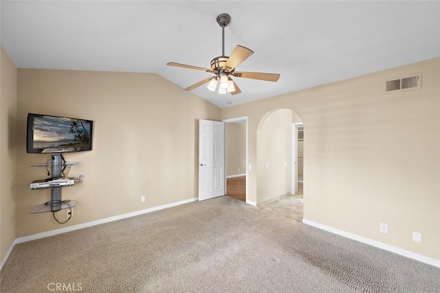 unfurnished bedroom featuring arched walkways, lofted ceiling, visible vents, baseboards, and carpet