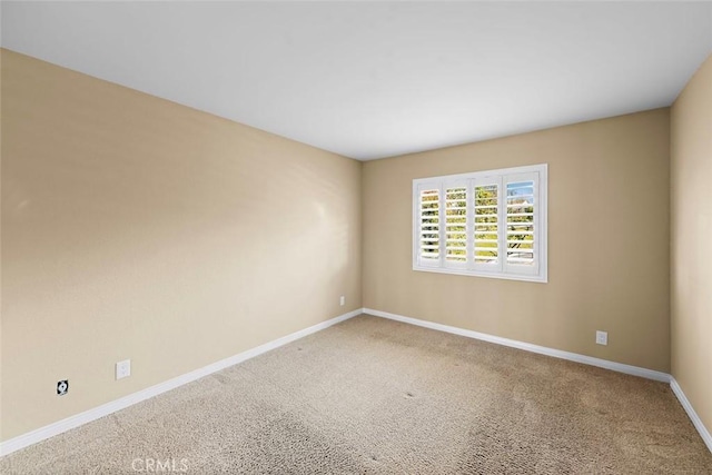 spare room featuring carpet and baseboards