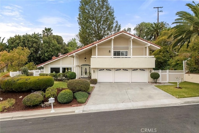 view of front facade with a garage, fence, concrete driveway, stucco siding, and a front yard