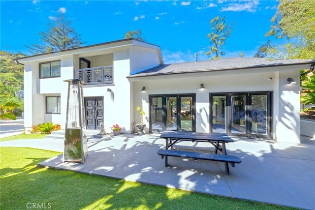 rear view of property featuring french doors, a patio, a balcony, and stucco siding