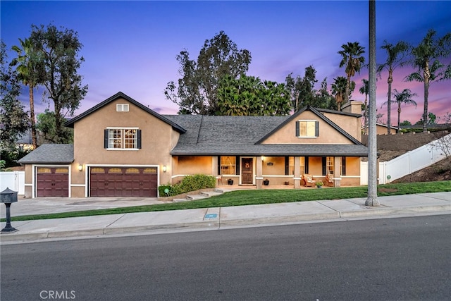 view of front of home featuring a porch, fence, driveway, and stucco siding