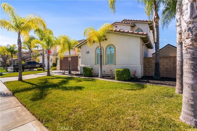 mediterranean / spanish-style house featuring driveway, a garage, fence, a front lawn, and stucco siding