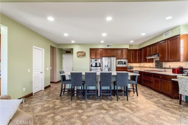 kitchen featuring visible vents, a kitchen island, a breakfast bar, stainless steel appliances, and recessed lighting