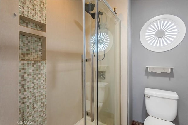 bathroom featuring toilet and a shower stall