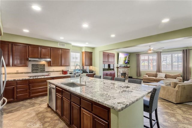 kitchen with visible vents, appliances with stainless steel finishes, a kitchen island with sink, a sink, and under cabinet range hood