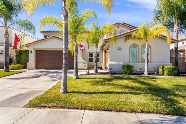 mediterranean / spanish home with a garage, driveway, a front yard, and stucco siding