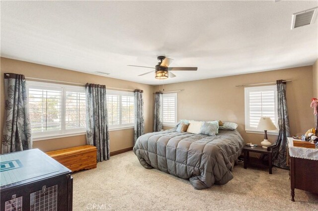 bedroom with visible vents, a ceiling fan, and light colored carpet