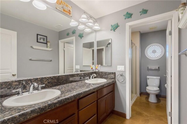 full bath featuring toilet, a sink, baseboards, and double vanity