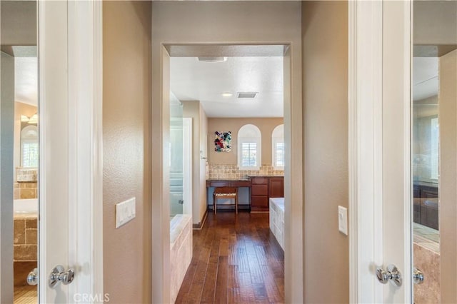 corridor featuring dark wood-style flooring and visible vents