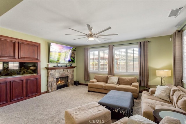 living room featuring a fireplace, visible vents, a ceiling fan, light carpet, and baseboards