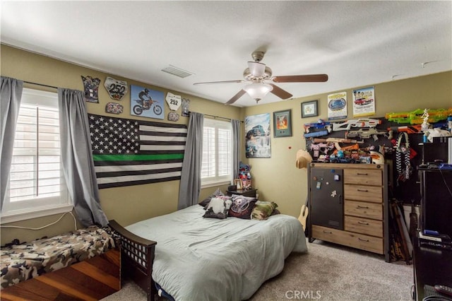 carpeted bedroom with a ceiling fan and visible vents