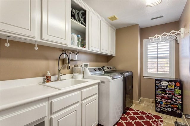 washroom featuring cabinet space, visible vents, a sink, and separate washer and dryer