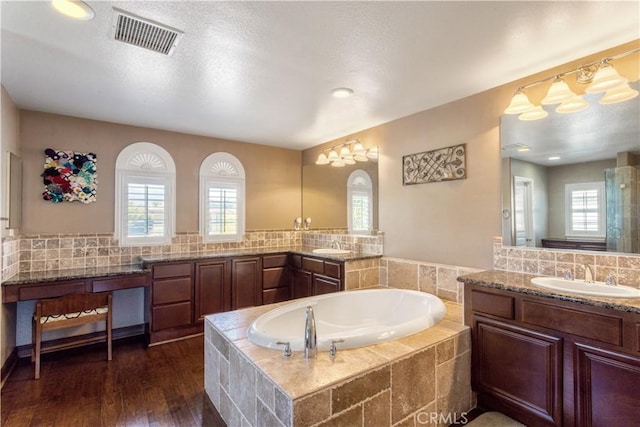 full bath featuring a garden tub, wood finished floors, a sink, visible vents, and a wealth of natural light