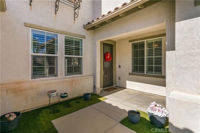 view of exterior entry featuring a tiled roof and stucco siding