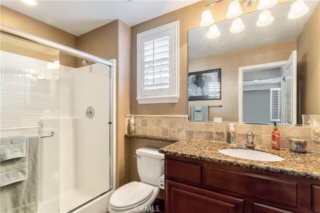 full bathroom featuring vanity, a shower stall, toilet, and decorative backsplash