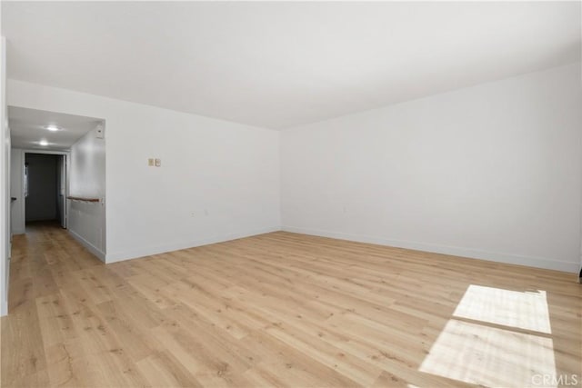 unfurnished room with baseboards and light wood finished floors