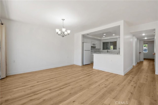 interior space featuring light wood-style flooring, baseboards, recessed lighting, and a chandelier