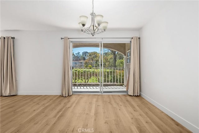 unfurnished dining area featuring baseboards, light wood-style floors, and a notable chandelier