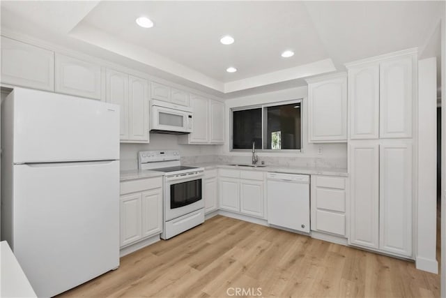 kitchen with a sink, white appliances, a raised ceiling, white cabinetry, and recessed lighting