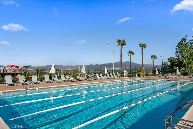 pool with fence, a patio, and a mountain view