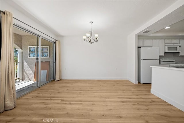 kitchen with an inviting chandelier, baseboards, light wood-type flooring, and white appliances