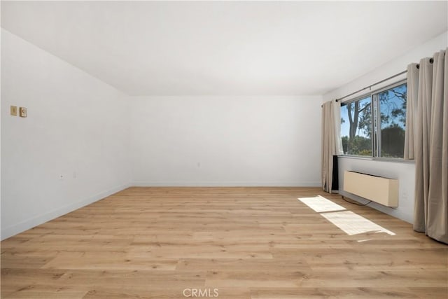 unfurnished room with baseboards, radiator heating unit, and light wood-style flooring