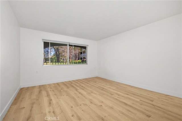 empty room featuring baseboards and light wood-type flooring