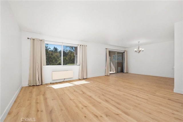 spare room with baseboards, radiator heating unit, a chandelier, and light wood-style flooring