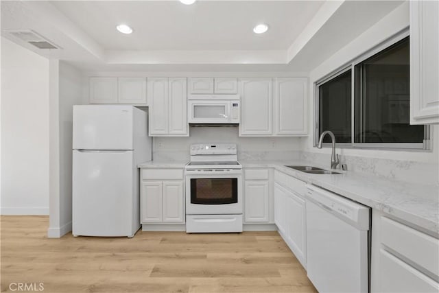 kitchen with a sink, white appliances, a raised ceiling, white cabinets, and visible vents