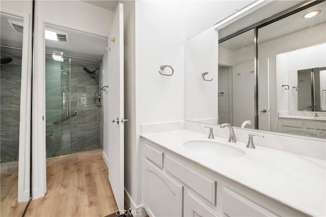 bathroom featuring visible vents, wood finished floors, vanity, and a stall shower