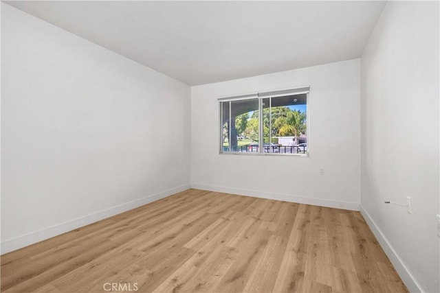 unfurnished room with light wood-type flooring and baseboards
