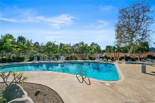 community pool with fence and a patio