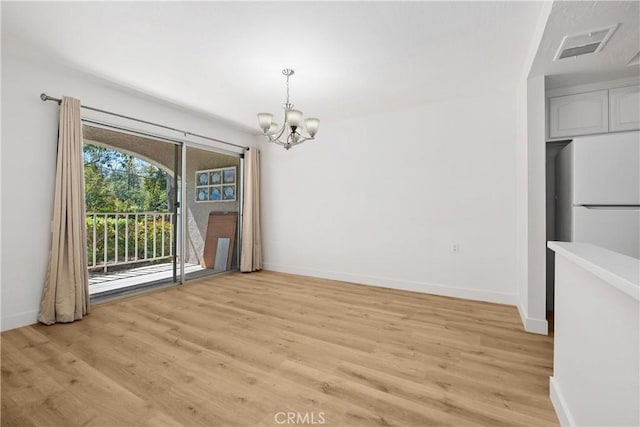 unfurnished dining area featuring baseboards, a notable chandelier, visible vents, and light wood finished floors