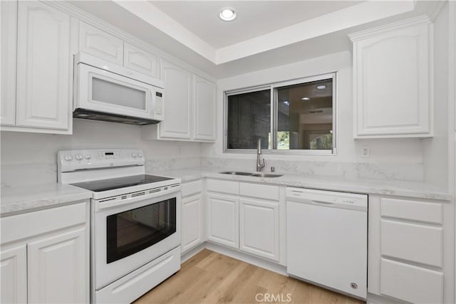 kitchen with white cabinets, light wood finished floors, a sink, and white appliances