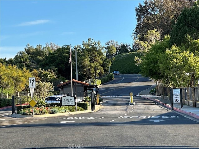 view of road featuring curbs, a gated entry, and traffic signs