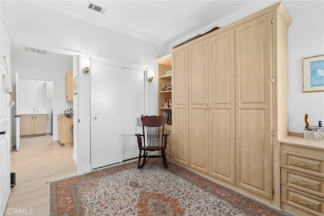 sitting room with ornamental molding, visible vents, and light wood finished floors