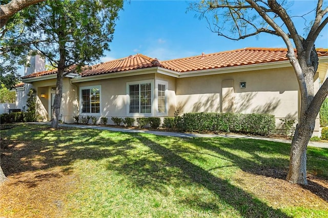 view of front of house with a front yard, a tile roof, and stucco siding