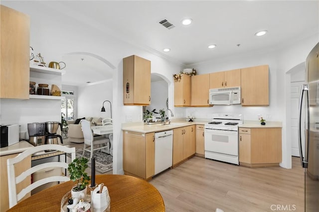 kitchen featuring arched walkways, light brown cabinetry, white appliances, and visible vents