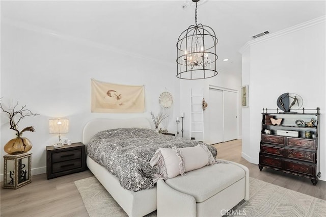 bedroom featuring a closet, wood finished floors, visible vents, and crown molding