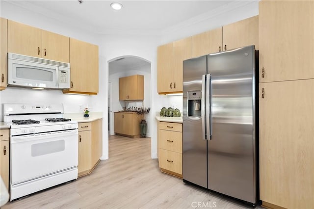 kitchen with arched walkways, light countertops, light wood-style flooring, light brown cabinets, and white appliances