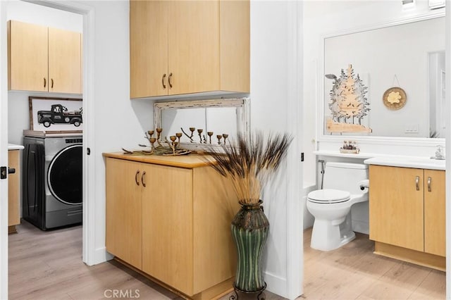 interior space featuring washer / clothes dryer, cabinet space, and light wood-style flooring